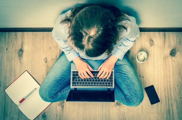 Vista superior do estudante está sentado no chão de madeira com laptop — Fotografia de Stock