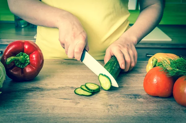 Woman cutting cucumber for salad - retro style Royalty Free Stock Images