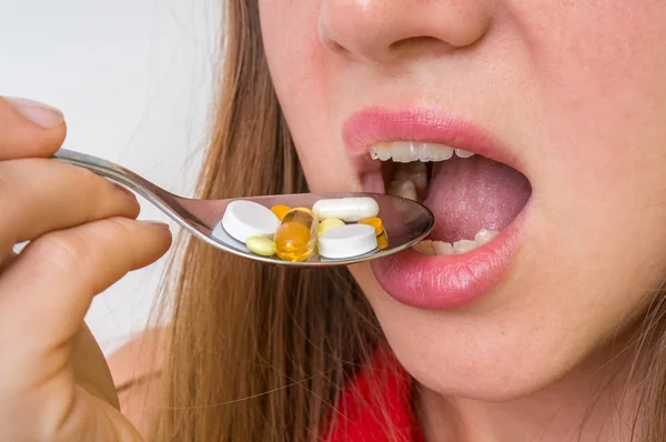 Mujer joven comiendo pastillas en una cuchara — Foto de Stock