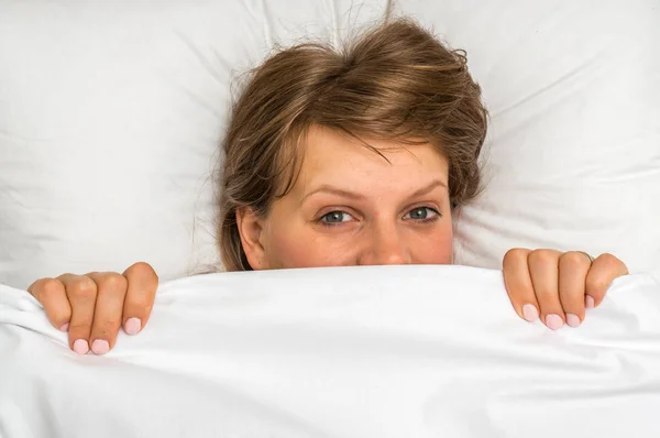 Attractive woman covering her face under blanket — Stock Photo, Image