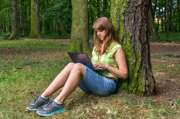 Parkta dizüstü bilgisayarı olan genç bir kadın.