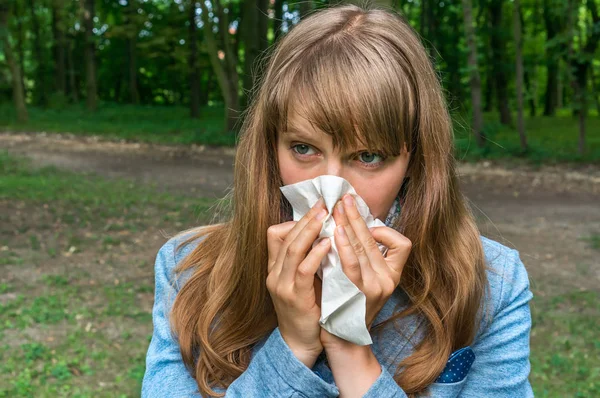 Woman with flu or allergy symptoms in park