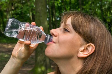 Kadın sıcak yaz gününde şişe su içiyor