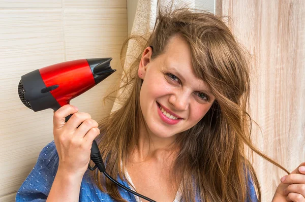 Mooie jonge vrouw droogt haar met een föhn — Stockfoto