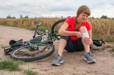 Woman with pain in knee after falling down from bicycle clipart