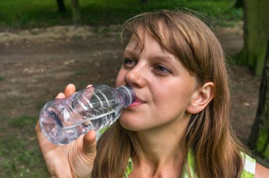 Kadın sıcak yaz gününde şişe su içiyor