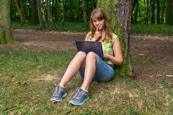 Parkta dizüstü bilgisayarı olan genç bir kadın.