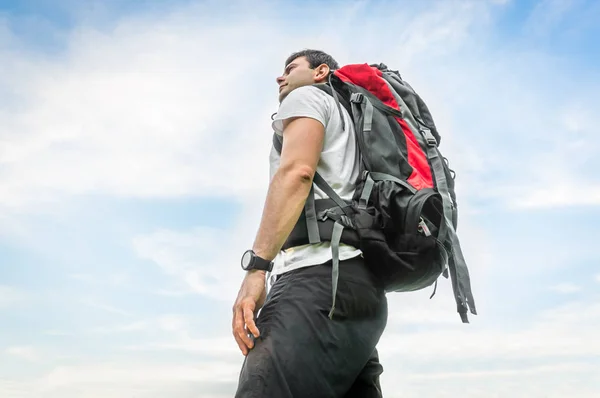 Voyageur homme avec sac à dos rouge sur fond bleu ciel — Photo