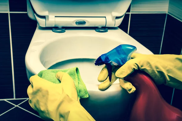 Woman is cleaning toilet bowl with a rag and disinfectant — Stock Photo, Image