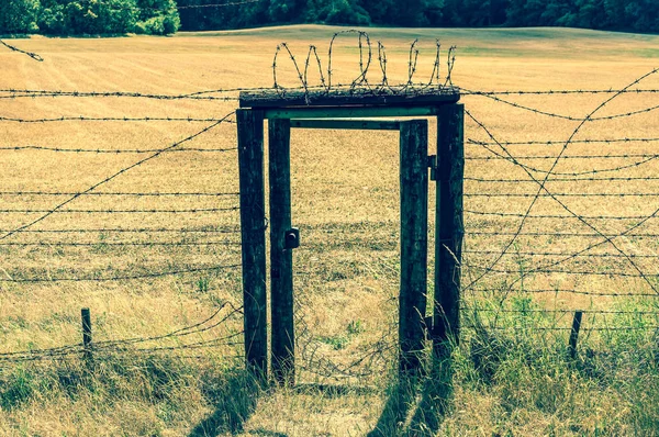 Restos de cortina de ferro com porta dentro cerca de arame — Fotografia de Stock