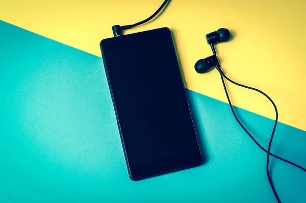 Hareket eden telefon ile renkli arka plan üzerinde kulaklık — Stok fotoğraf