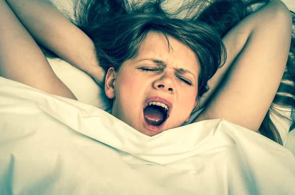 Mujer joven bostezando en la cama después de dormir - estilo retro — Foto de Stock