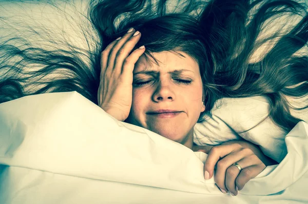 Woman in bed having headache in the morning - retro style — Stock Photo, Image