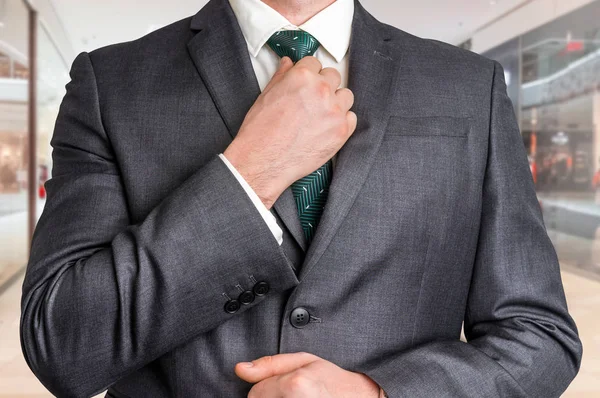 Homme d'affaires en noir ajustant sa cravate dans le centre commercial — Photo
