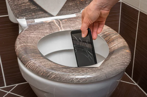 Femme jetant téléphone portable dans la cuvette des toilettes — Photo