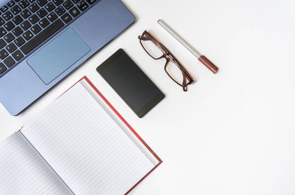 Workplace with laptop and smartphone on white wooden table