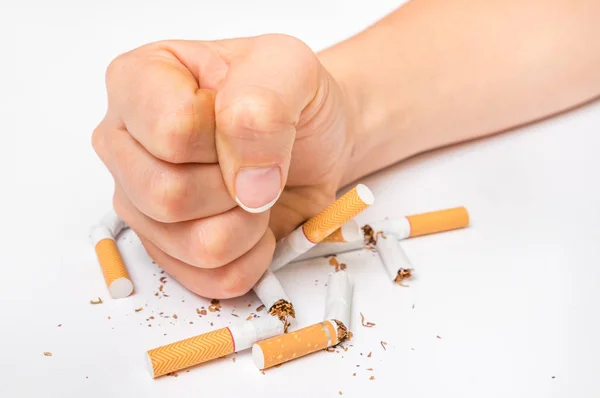 Human fist and pile of broken cigarettes - stop smoking concept — Stock Photo, Image