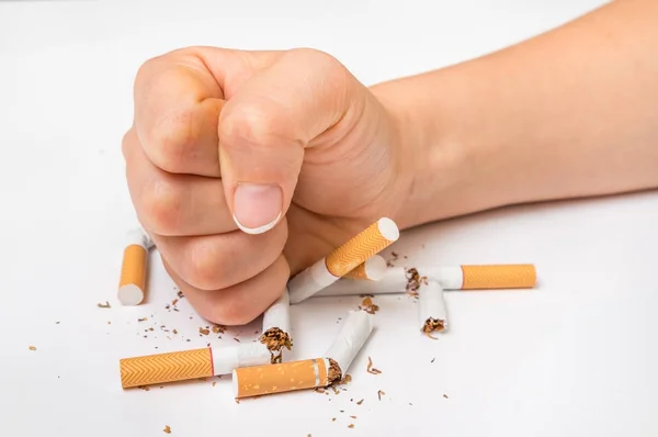 Человеческий кулак и куча сломанных сигарет - бросить курить — стоковое фото