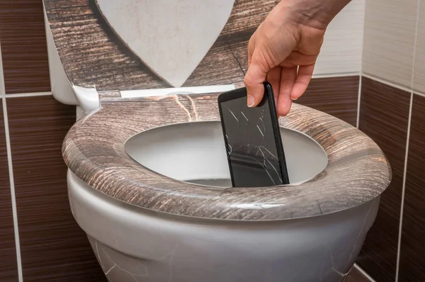 Woman throwing mobile phone in the toilet bowl — Stock Photo, Image