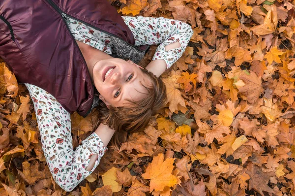 Attraktive Frau liegt über Herbstlaub im Park — Stockfoto