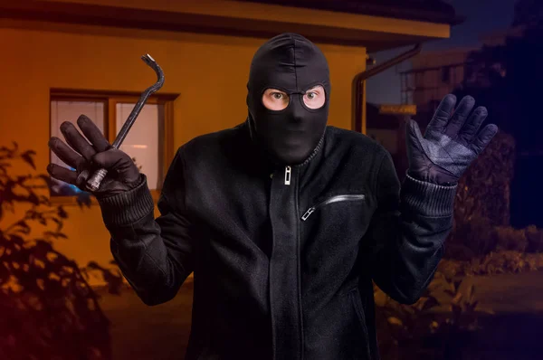 Arresterade maskerad tjuv i balaclava med kofot och upphöjda armar — Stockfoto