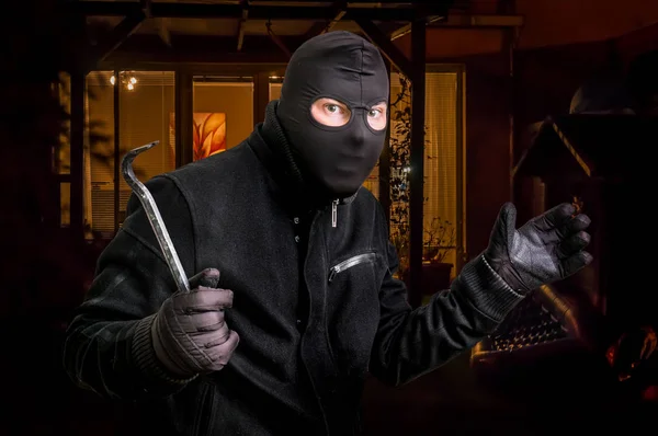 Maskerad tjuv i balaclava med kofot vill råna ett hus — Stockfoto