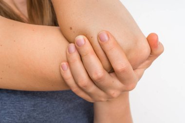 Kadın ile dirsek ağrısı ağrıyan kolunu tutuyor