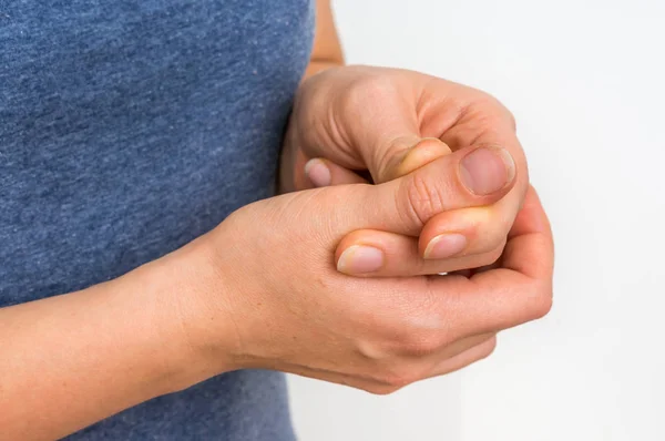 Женщина с болями в пальцах держит свой больной палец — стоковое фото