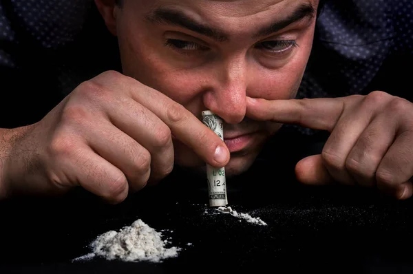 Hombre drogadicto inhalando cocaína en polvo con billetes laminados — Foto de Stock