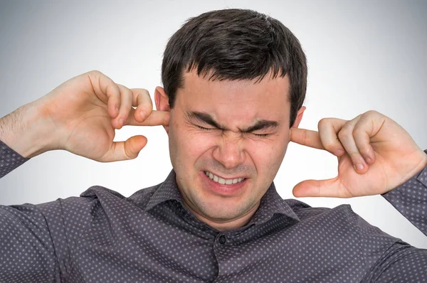 Man closes ears with fingers to protect from loud noise — Stock Photo, Image