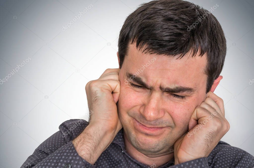 Man covering his ears to protect from loud noise