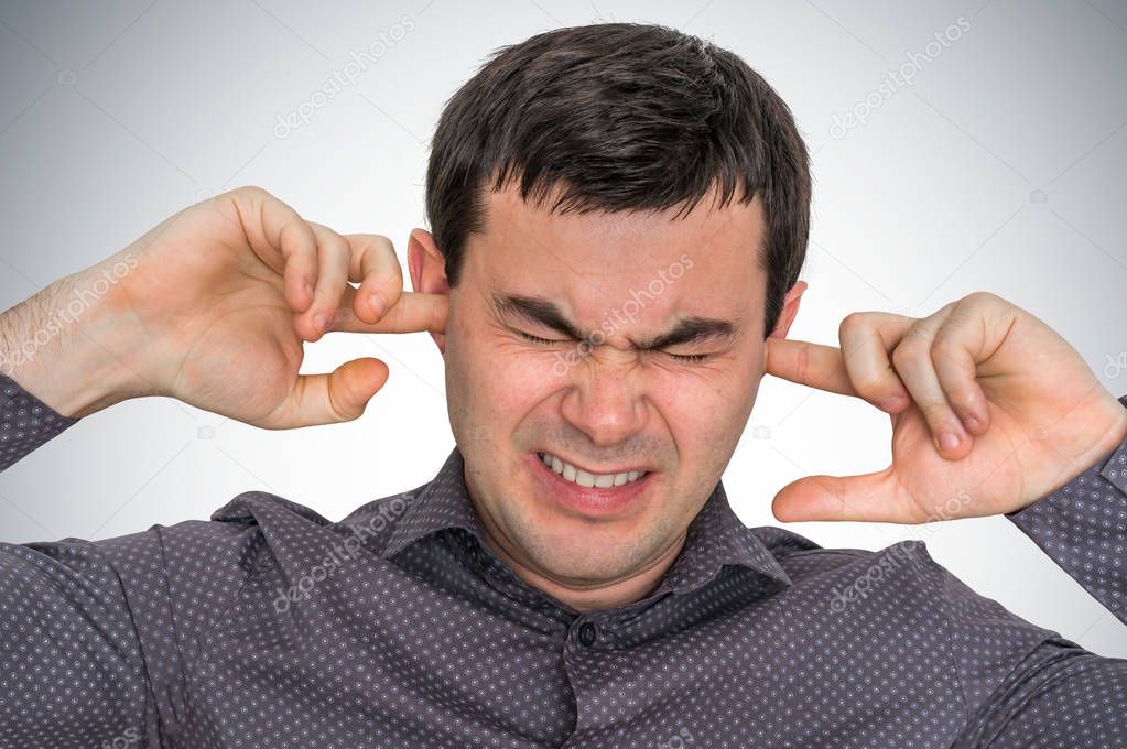 Man closes ears with fingers to protect from loud noise