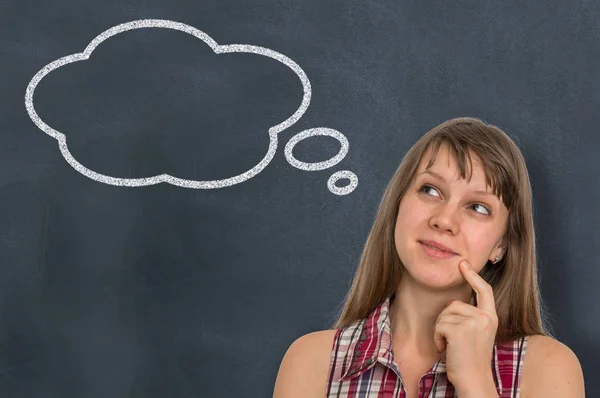 Thoughtful woman with thought bubble on blackboard Stock Image