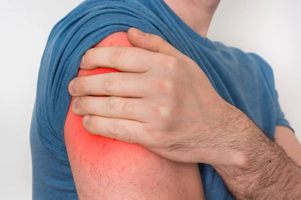 Man met pijn in de schouder houdt zijn pijnlijke arm — Stockfoto