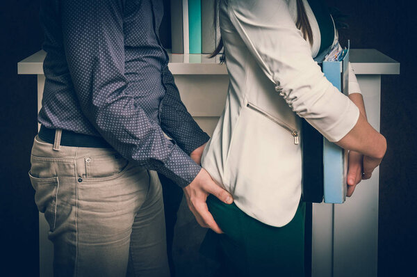 Мужчина трогает женскую задницу - сексуальные домогательства в офисе
