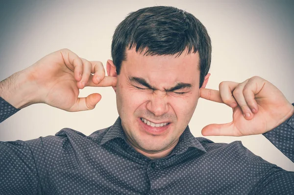 Man closes ears with fingers to protect from loud noise — Stock Photo, Image
