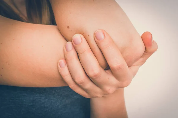 Женщина с болью в локте держит свою больную руку — стоковое фото