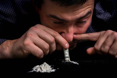 Keş adam kokain toz haddelenmiş banknot ile burundan enfiye şeklinde çekmek
