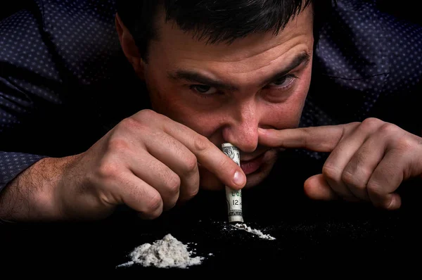 Джинсовий чоловік хропить кокаїновий порошок з рулонною банкнотою — стокове фото