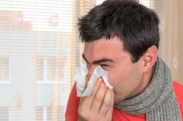 Sick man with flu or cold sneezing into handkerchief