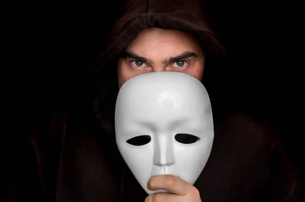 Hombre misterioso de negro escondiendo su cara detrás de la máscara blanca — Foto de Stock