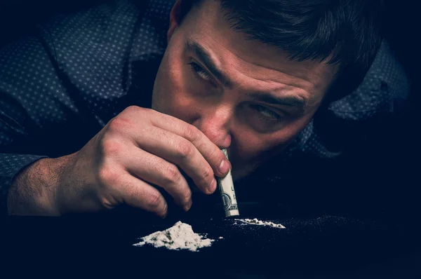 Junkie man snorting cocaine powder with rolled banknote — Stock Photo, Image