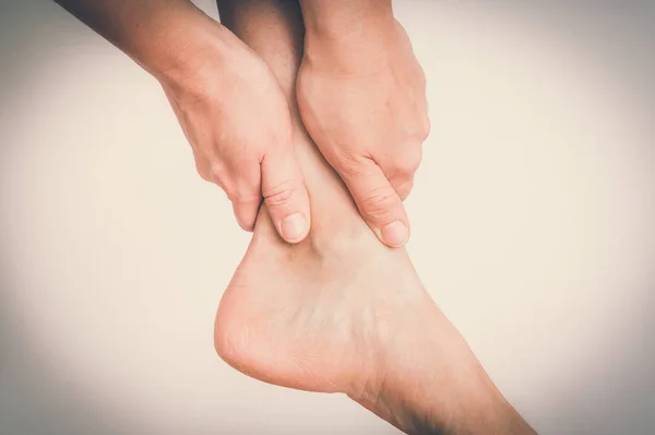 Mujer con dolor en el tobillo sosteniendo su pierna dolorida - estilo retro — Foto de Stock