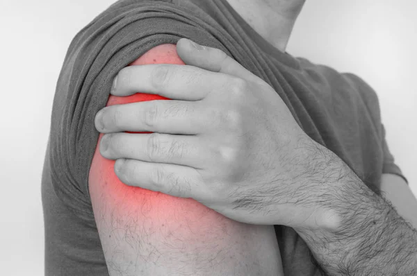 Homem com dor no ombro está segurando seu braço dolorido — Fotografia de Stock