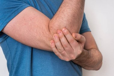 Adam ile dirsek ağrısı ağrıyan kolunu tutuyor