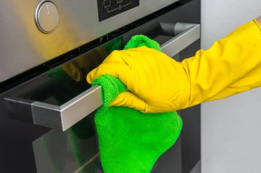 El olarak eldiven yeşil bez ile fırın mutfak silme