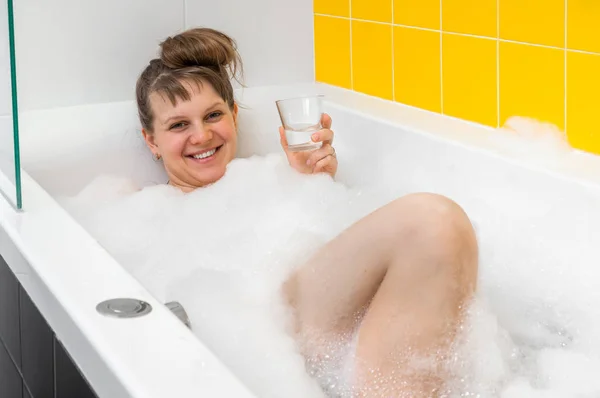 Hermosa mujer joven está tomando un baño relajante con espuma —  Fotos de Stock