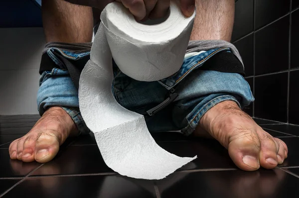 Człowiek cierpi z powodu biegunki jest siedząc na muszli klozetowej — Zdjęcie stockowe