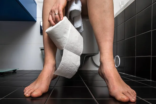 Woman suffers from diarrhea is sitting on toilet bowl — Stock Photo, Image