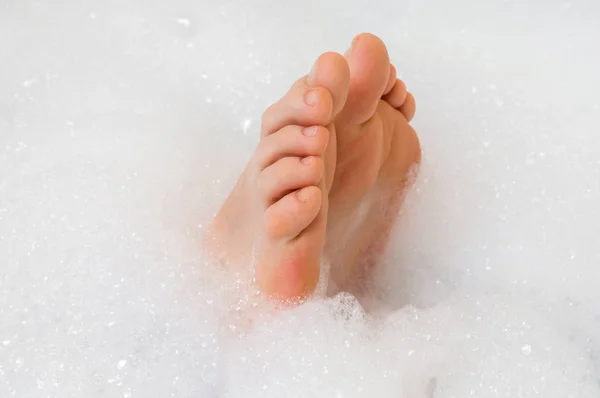 Bei piedi femminili nella vasca da bagno con schiuma — Foto Stock